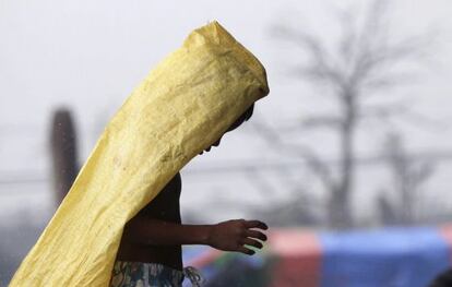 Un niño camina bajo la lluvia cubriéndose con un plástico en Tacloban (Filipinas)