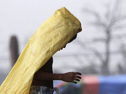 Un niño camina bajo la lluvia cubriéndose con un plástico en Tacloban (Filipinas)