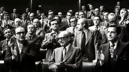 El presidente del Gobierno, Adolfo Suárez (a la derecha), y los vicepresidentes Enrique Fuentes Quintana (a la izquierda)y el teniente general Manuel Gutiérrez Mellado, aplauden en pie desde sus escaños, junto al resto de diputados, tras la aprobación de la Ley de Amnistía el 14 de octubre de 1977.