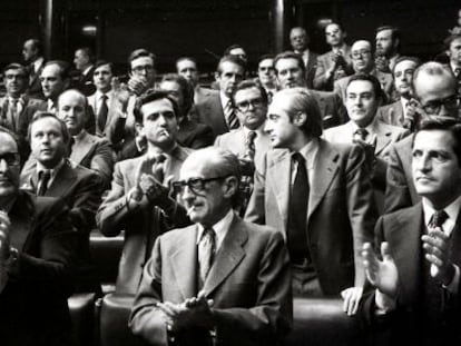 El presidente del Gobierno, Adolfo Suárez, (1º d), y los vicepresidentes Enrique Fuentes Quintana (3º d) y el teniente general Manuel Gutiérrez Mellado (2º d), aplauden en pie desde sus escaños en el Congreso, junto al resto de diputados, tras la aprobación de la ley de Amnistía, consagrando la reconciliación entre vencedores y vencidos de la Guerra Civil.