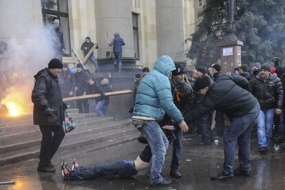 Manifestantes pró-Rússia arrastam um homem ferido durante confrontos com apoiadores do governo ucraniano na Carcóvia, Ucrânia.