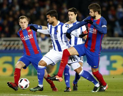 El delantero de la Real Sociedad, Willian José (centro) , lucha un balón con el defensa del Barcelona Gerard Piqué (derecha).