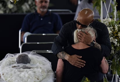 El hijo de Pelé, Edinho se abraza con una mujer junto al cuerpo de su padre, durante el velorio de hoy lunes en el estadio Vila Belmiro, en Santos (Brasil).