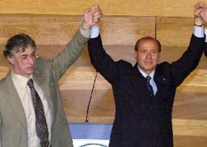 El magnate y candidato de la derecha, Silvio Berlusconi, levanta la mano de su socio de coalición, Umberto Bossi, ayer en Milán.