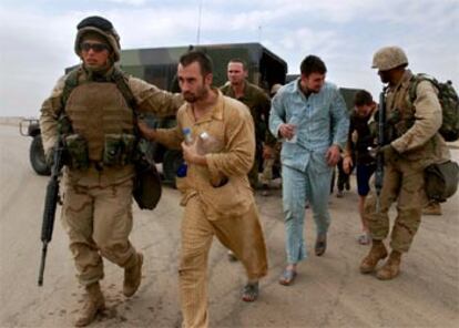 Dos de los siete <i>marines</i> rescatados ayer (en pijama) son escoltados por sus compañeros para coger un transporte, ayer, al sur de Irak.