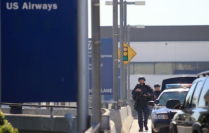 Un agente de polic&iacute;a camina, arma en mano, por uno de los aparcamientos del aeropuerto. 