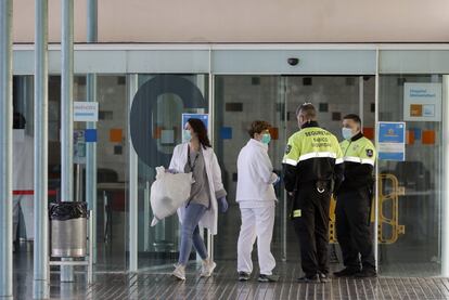 Dos agentes de seguridad junto a dos enfermeras en la entrada principal del hospital del Mar de Barcelona, este sábado.