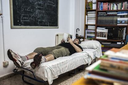 Carlos descansa en una cama dispuesta en la biblioteca de la asociación. La falta de espacio para más usuarios en la casa del cura les ha animado a alquilar dos pisos para cubrir la demanda.
