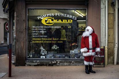 Un Papa Noel entrega caramelos a las puertas de una funeraria.