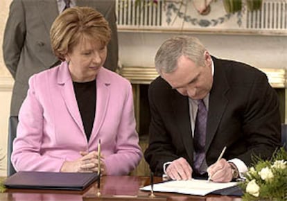 La presidenta de Irlanda, Mary McAleese, observa como el primer ministro, Bertie Ahern, firma la disolución del Parlamento.