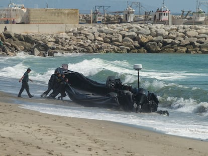 Agentes de la Guardia Civil arrastran una lancha abandonada por los narcos tras una persecución, en la playa del Tonelero, en La Atunara (Cádiz).