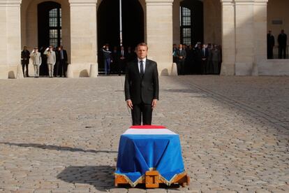 El presidente francés, Emmanuel Macron, se para frente al ataúd cubierto de banderas del fallecido.