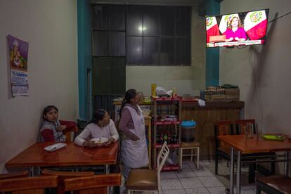 Women watching Peruvian President Dina Boluarte's message to the nation, inside a restaurant in Juliana on Sunday.