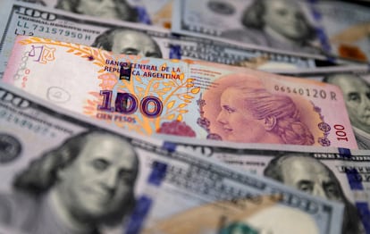 Un billete de cien pesos argentinos junto a dólares estadounidenses