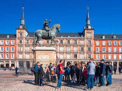 Un grupo de turistas atiende a las explicaciones de un gu&iacute;a en la plaza Mayor de Madrid.