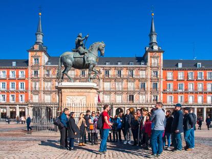 Un grupo de turistas atiende a las explicaciones de un guía en la plaza Mayor de Madrid.