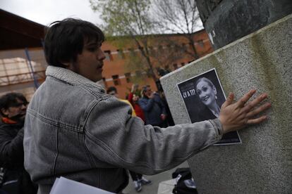 Un estudiante pega un cartel de Cristina Cifuentes en la URJC.