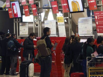 Varias personas guardan cola junto a los mostradores de facturación de la Terminal T4 del aeropuerto de Madrid-Barajas. 