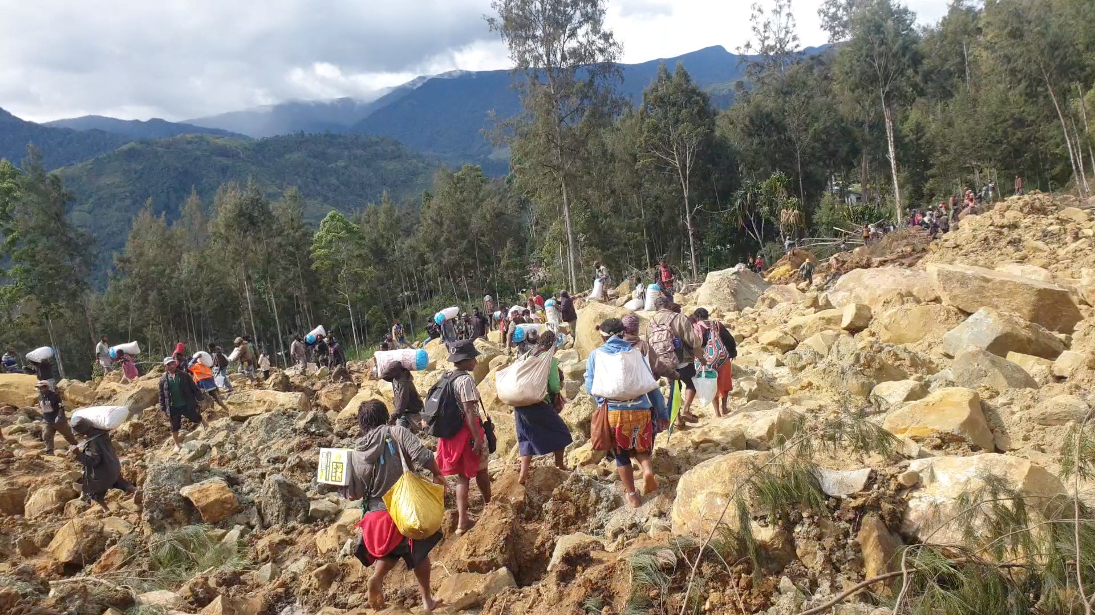 Un grupo de personas se moviliza entre las rocas este domingo tras el corrimiento de tierra que ha afectado al norte de Papúa Nueva Guinea.
