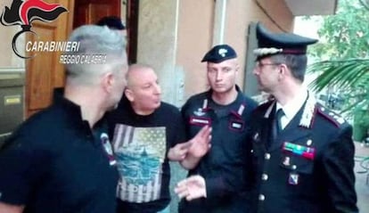 Giuseppe Giorgi sale de la vivienda donde se ocultaba rodeado de polic&iacute;as.