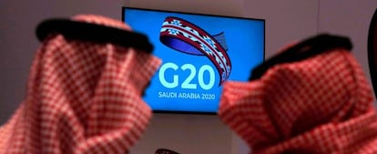 Dos funcionarios saudíes siguen en un televisor la reunión de ministros de Finanzas y gobernadores de los bancos centrales del G20 en Riad.