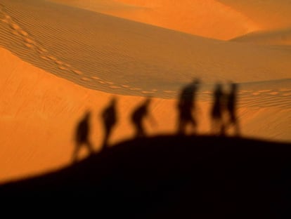 Las sombras reflejadas de un grupo de personas caminando por el desierto.
Getty Images/EyeEm