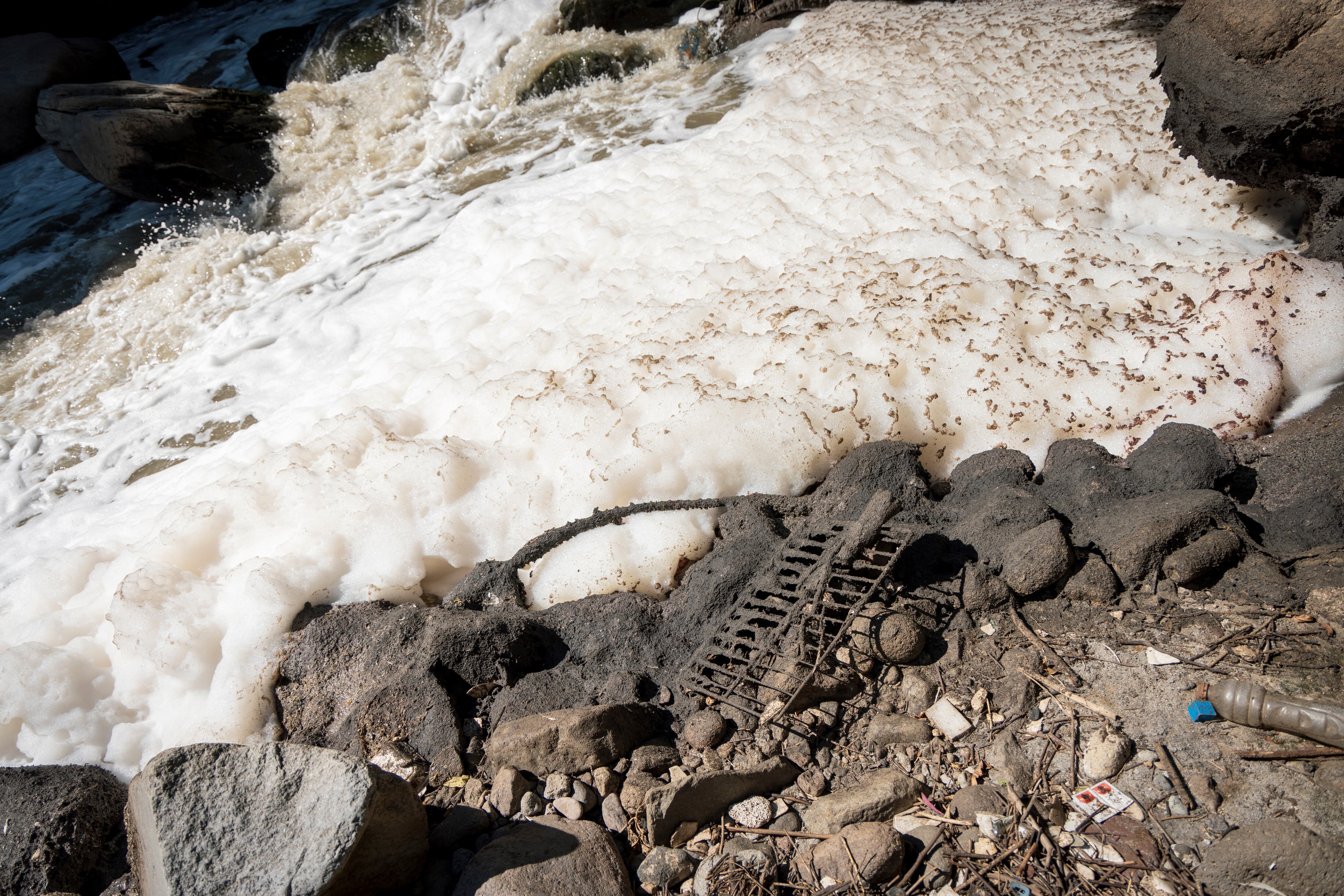 La espuma blanca en las orillas del río son los tensoactivos que infectan el agua, mientras que entre las rocas se estanca materia orgánica en descomposición.