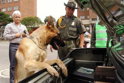 Un agente de policía, con un perro adiestrado, registra un coche en busca de explosivos en Medellín.