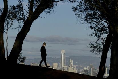 Un joven, con mascarilla, camina sobre Tank Hill. Al fondo, San Francisco.