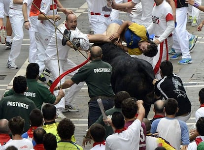 Un joven es empitonado en la calle Estafeta durante el sexto encierro de los sanfermines.