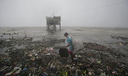 Un hombre busca entre los restos dejados tras el paso del tifón Koppu, en Navotas, al norte de Manila, este domingo.