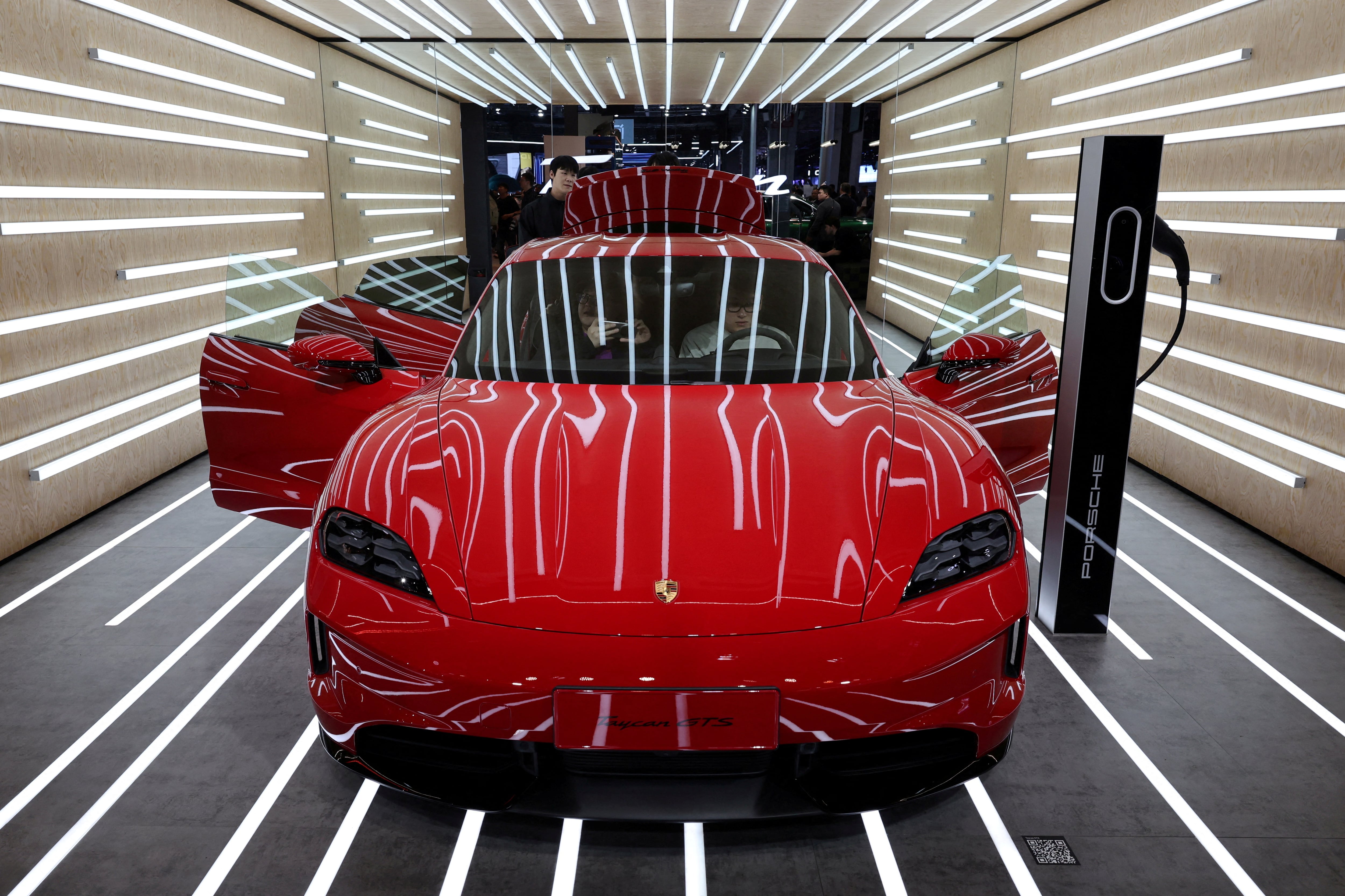 La gente observa el vehículo eléctrico (EV) Porsche Taycan GTS.