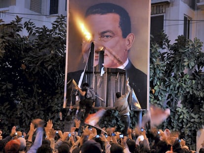 Unos manifestantes arrancan un cartel del presidente egipcio, Hosni Mubarak, durante una concentración en el marco de las revueltas de la Primavera Árabe en Alejandría (Egipto), el 25 de enero de 2011.