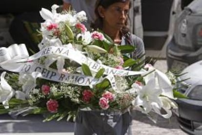 Una mujer transporta un ramo de flores a la entrada del tanatorio de la empresa Servisa, en A Coruña, donde está instalada la capilla ardiente con los restos mortales de la empresaria gallega Rosalía Mera.