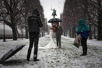 La nieve que cayó desde la madrugada de este martes en buena parte del norte de Francia y en los Pirineos causó abundantes problemas de circulación, como en París, donde se suspendieron más de un centenar de líneas de autobús urbano y se cerró el acceso a la torre Eiffel. En la imagen, una pareja de recién casados se fotografía mientas cae la nieve.