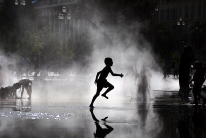 Un niño juega entre la niebla producida por una fuente en el sur de Francia, el 2 de agosto de 2017.