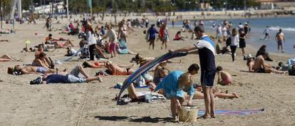 Decenas de ba&ntilde;istas toman el sol ayer en la playa del Postiguet en Alicante.