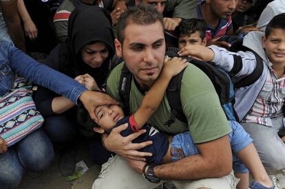 Un hombre trata de proteger a su hijo junto a un grupo de refugiados que intenta cruzar de Grecia a Macedonia.