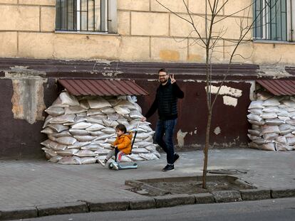 Un hombre hace el gesto de la victoria mientras pasea con un niño por una calle de la ciudad de Odesa este jueves.