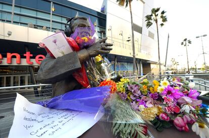 Ramos de flores y mensajes en recuerdo de Jerry Buss envuelven un busto dedicado al locutor Chick Hearn.