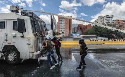 Un grupo de activistas opositores al Gobierno se enfrentan a un camión de la policía que emplea chorros de agua para disuadir a los manifestantes en una protesta en Caracas, el 19 de junio de 2017.