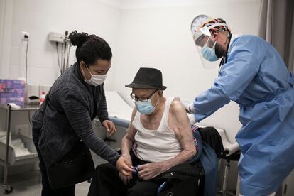 En la imagen, el doctor Gerard Suárez atiende a Rafael, de 96 años, que está acompañado de su cuidadora, Ana.