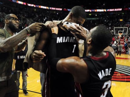 LeBron James, vestido de calle, y Wade celebran con Bosh su triple decisivo.