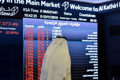 Un saudí pasa ante un monitor con datos de precios del índice Tadawul, en Riad.