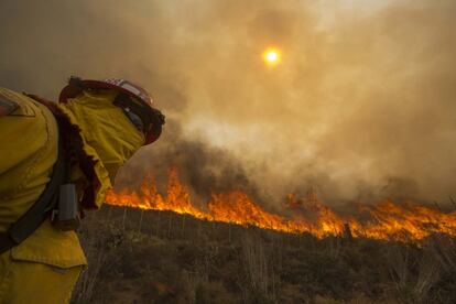 Un bombero vigila las llamas en una ladera de Point Mugu, California