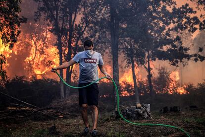 Un hombre usa una manguera para extinguir el incendio en Oliveira De Azemeis, este lunes.
