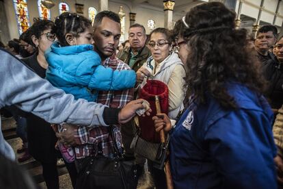 Fieles dando limosna durante la misa en la iglesia del Divino Niño.