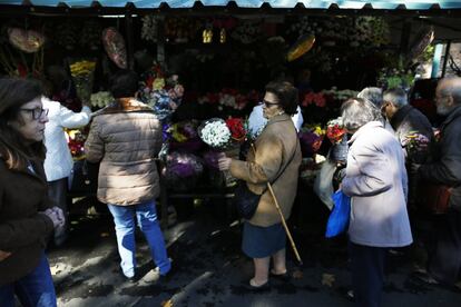 Un grupo de mujeres compran flores antes de entrar en el cementerio madrileño de La Almudena.