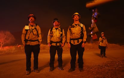 Un grupo de bomberos vigilan mientras el incendio Hughes arde al norte de Los Ángeles, este miércoles cerca de Castaic, California. 