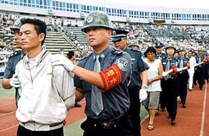 Policías chinos conducen a un grupo de condenados por narcotráfico a la lectura pública de sus sentencias en un estadio de la ciudad de Guiyang.